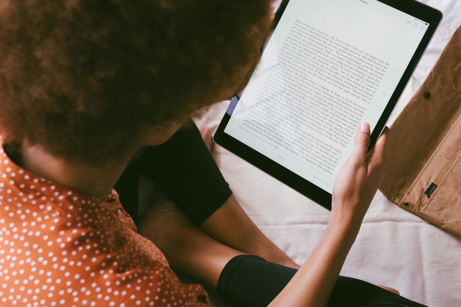 Woman reading an ebook on a tablet indoors, relaxed modern lifestyle.