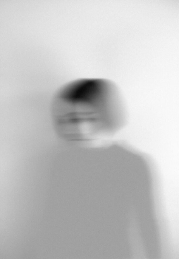 Artistic blurred grayscale portrait capturing motion and emotion.