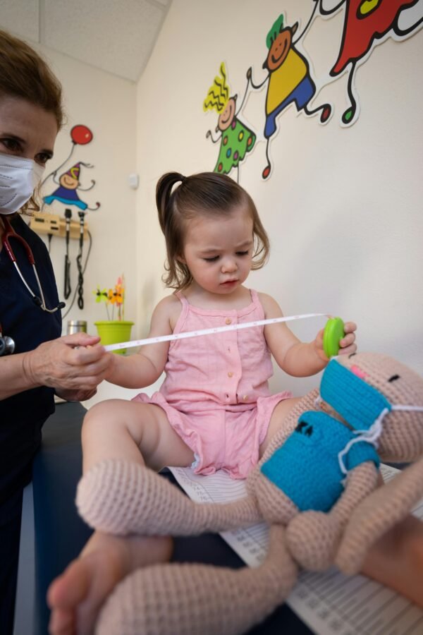 A pediatrician assists a toddler during a routine check-up at a medical clinic.